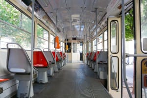 Lubbock Lease Homes: Interior of an empty tram used for Lubbock public transportation, featuring rows of red and gray plastic seats, large windows on both sides with sunlight streaming in. The open tram doors and metallic floor suggest a modern, clean commute.